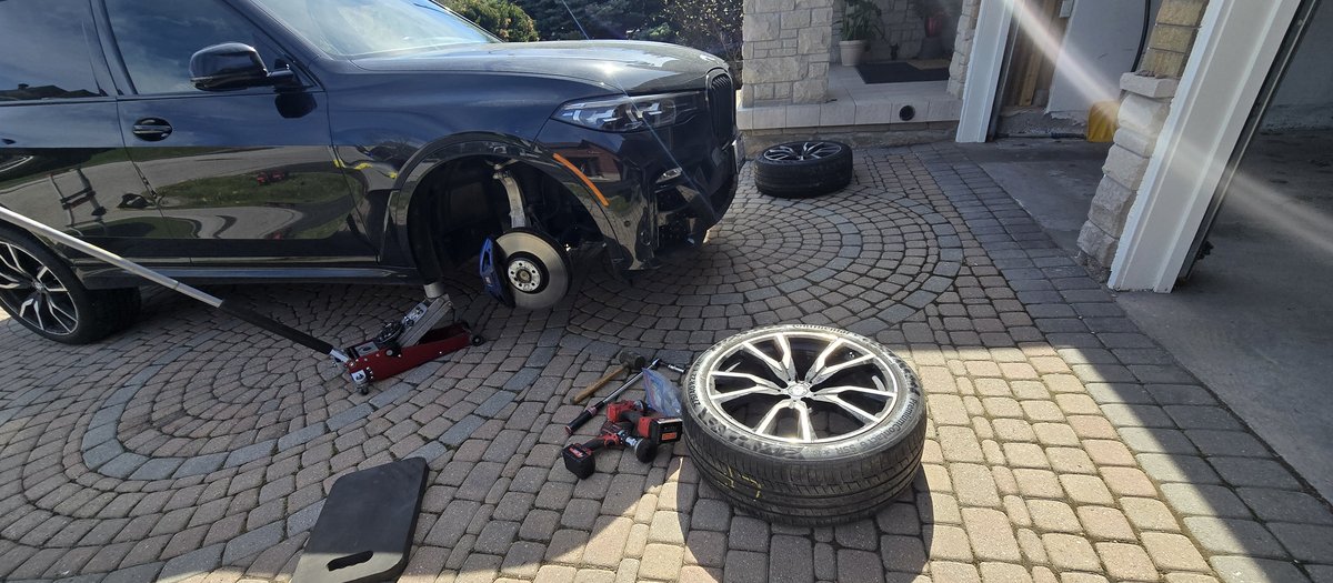 Black luxury SUV on a jack in a Markham driveway during a Sparky X mobile tire service — wheel off, tools laid out