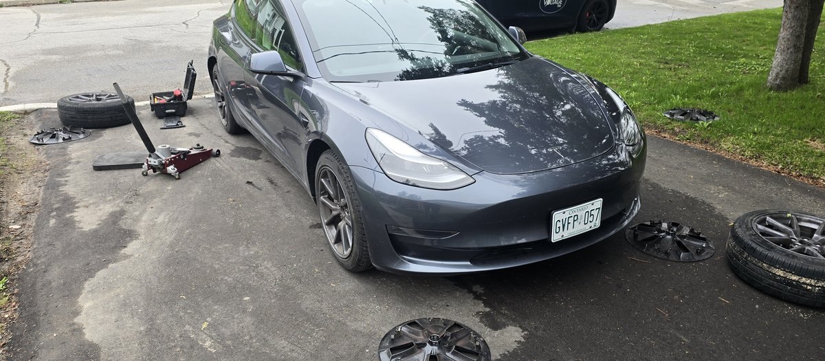 Grey Tesla sedan in a North York driveway during a Sparky X mobile tire service — jack and wheels in the foreground