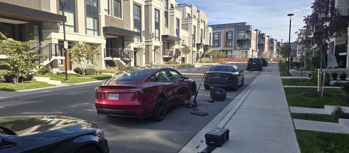 Red Tesla sedan on a jack at the curb during a Sparky X mobile tire service in Richmond Hill