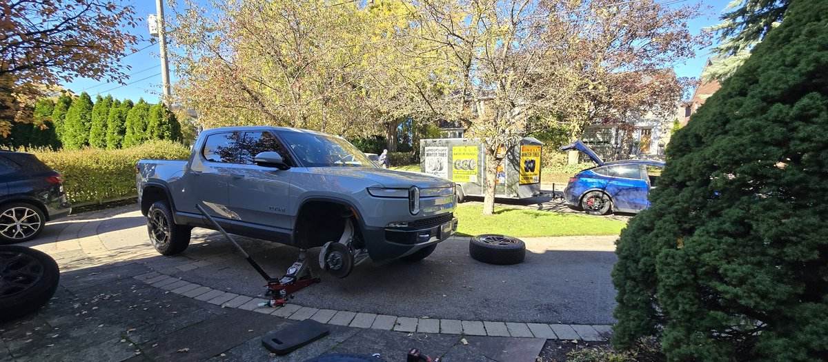 Grey pickup truck on a jack with the front wheel off during a Sparky X mobile tire service in Toronto — the Sparky X service trailer behind
