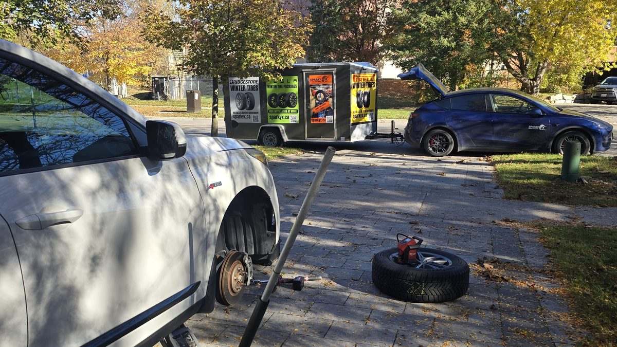 Sparky X seasonal tire changeover at a customer's home — front wheel off, vehicle safely supported, the next set ready to go on
